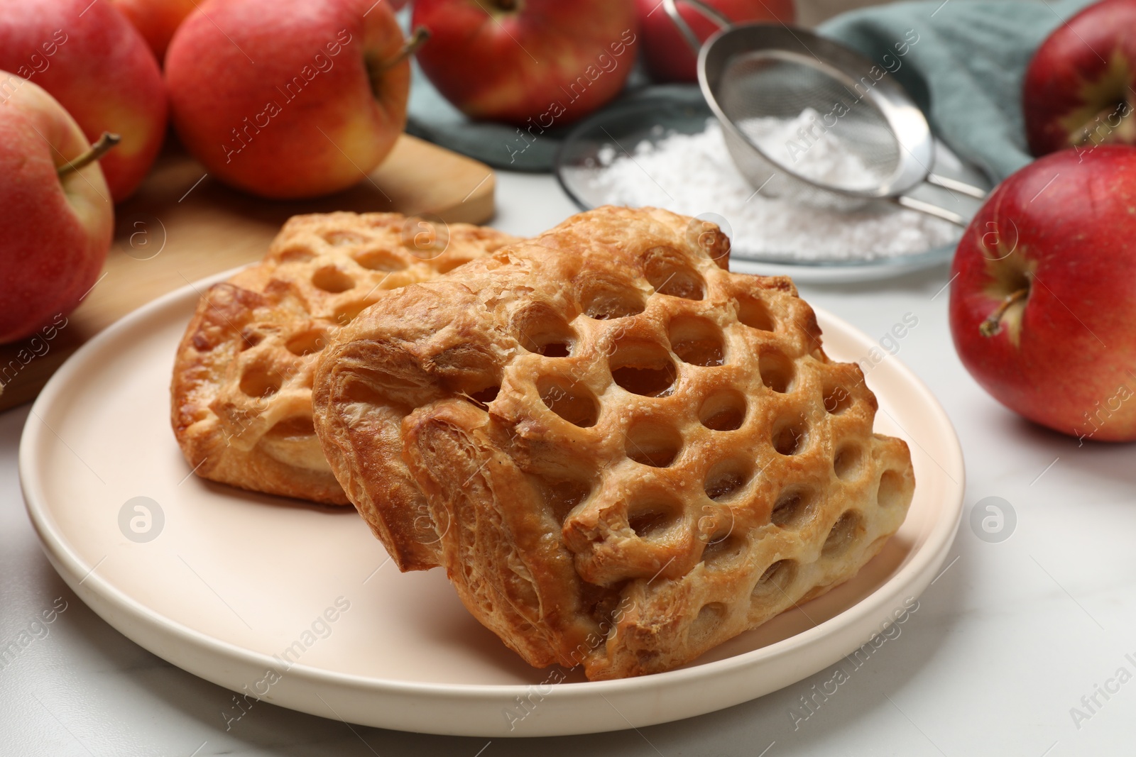 Photo of Delicious puff pastries with apples on white wooden table, closeup