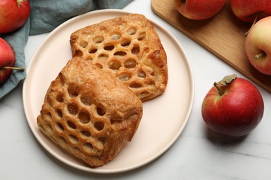 Delicious puff pastries with apples on white wooden table, flat lay