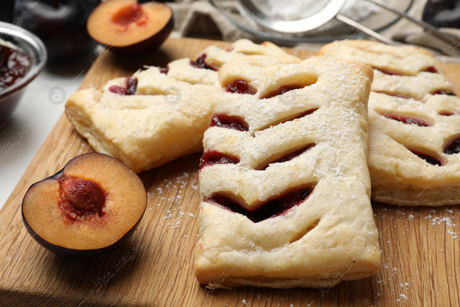 Photo of Delicious puff pastries and plums on table, closeup