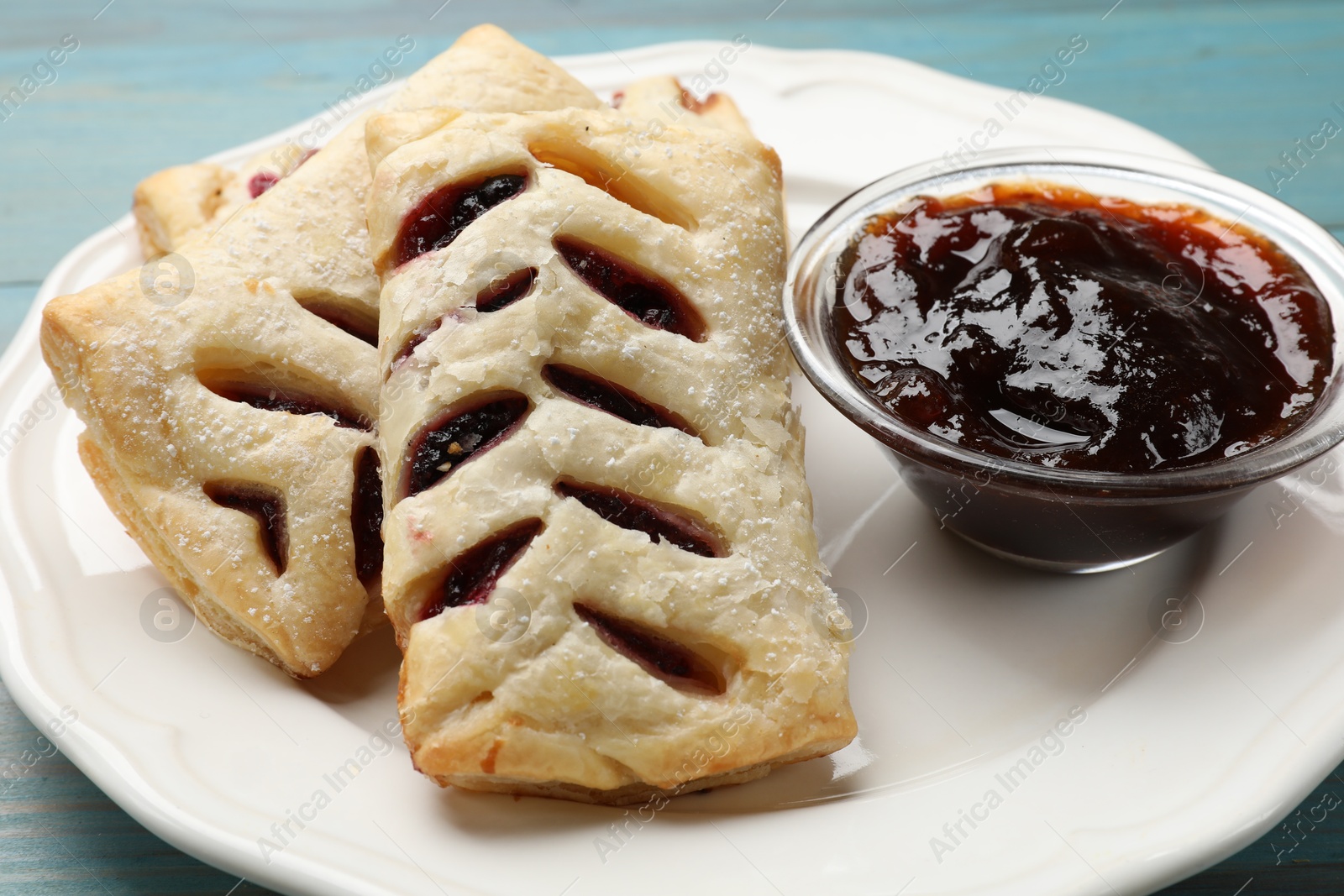 Photo of Delicious puff pastries and jam on table, closeup