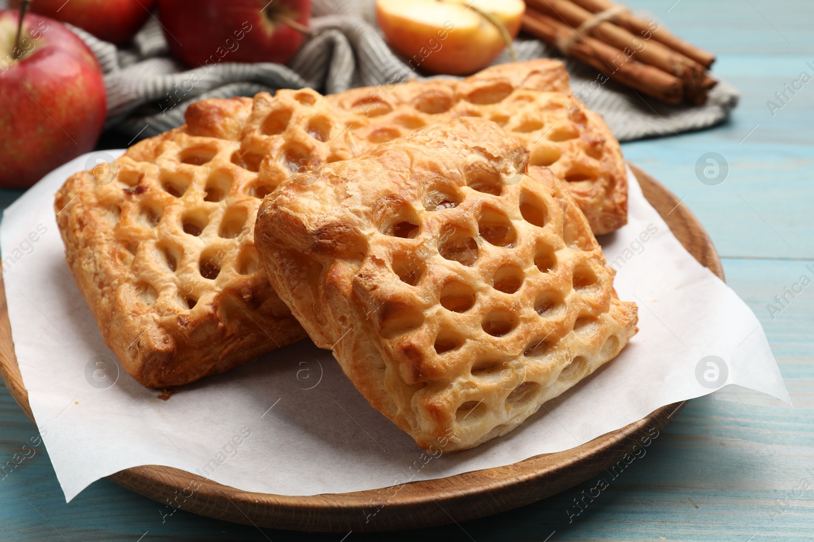 Photo of Delicious puff pastries with fruit filling on light blue wooden table, closeup