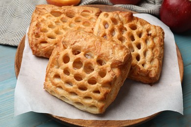 Photo of Delicious puff pastries with fruit filling on light blue wooden table, closeup