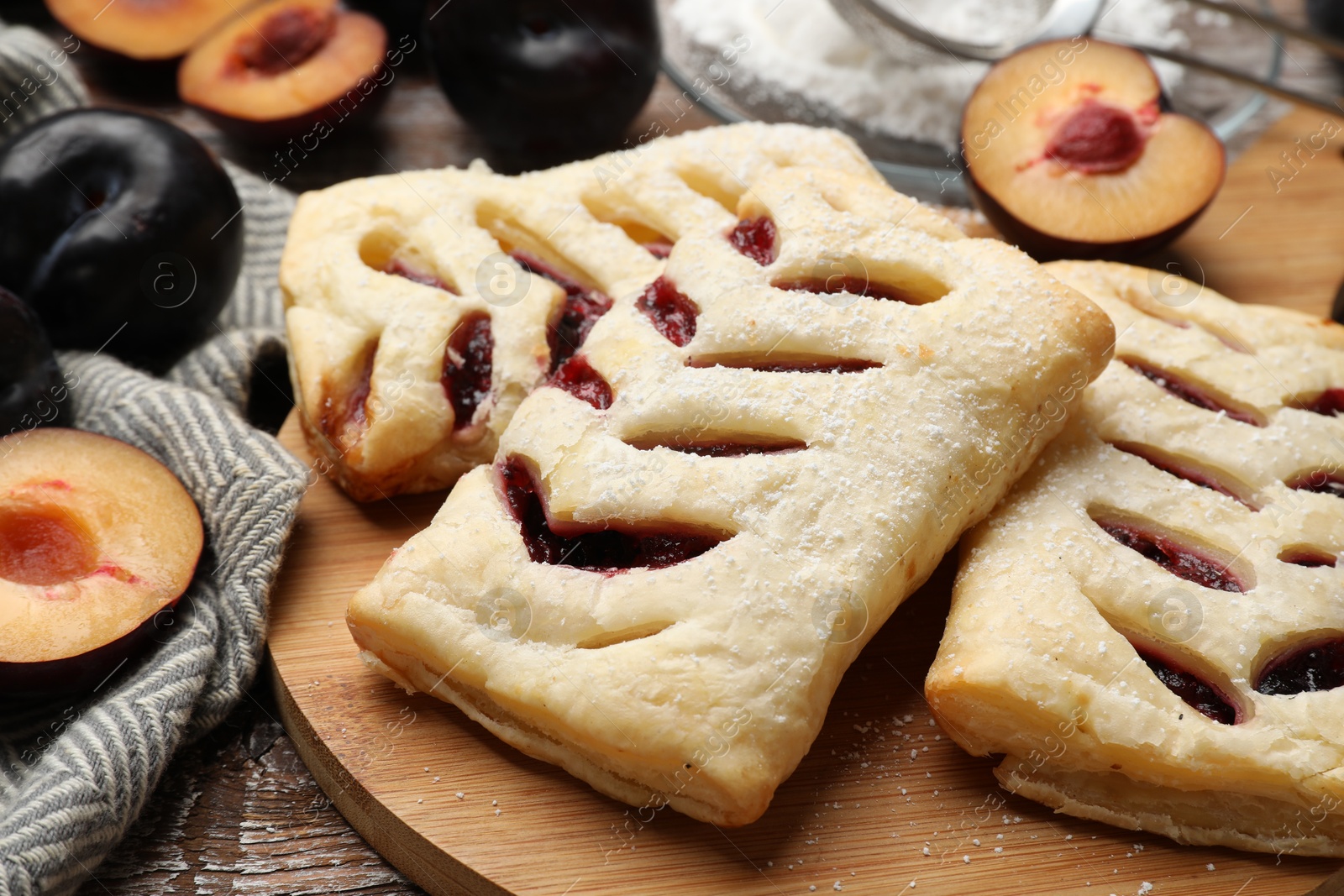 Photo of Delicious puff pastries and plums on table, closeup