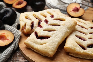 Photo of Delicious puff pastries and plums on table, closeup