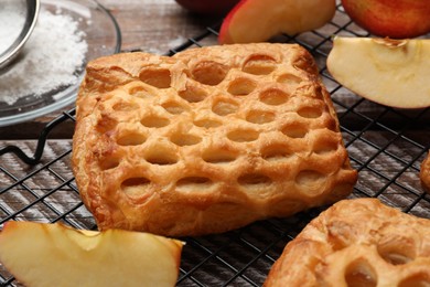 Delicious puff pastries with fruit filling and apples on wooden table, closeup