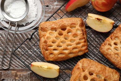 Photo of Delicious puff pastries with fruit filling, apples and powdered sugar on wooden table, top view