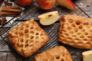 Photo of Delicious puff pastries with fruit filling and apples on wooden table, top view