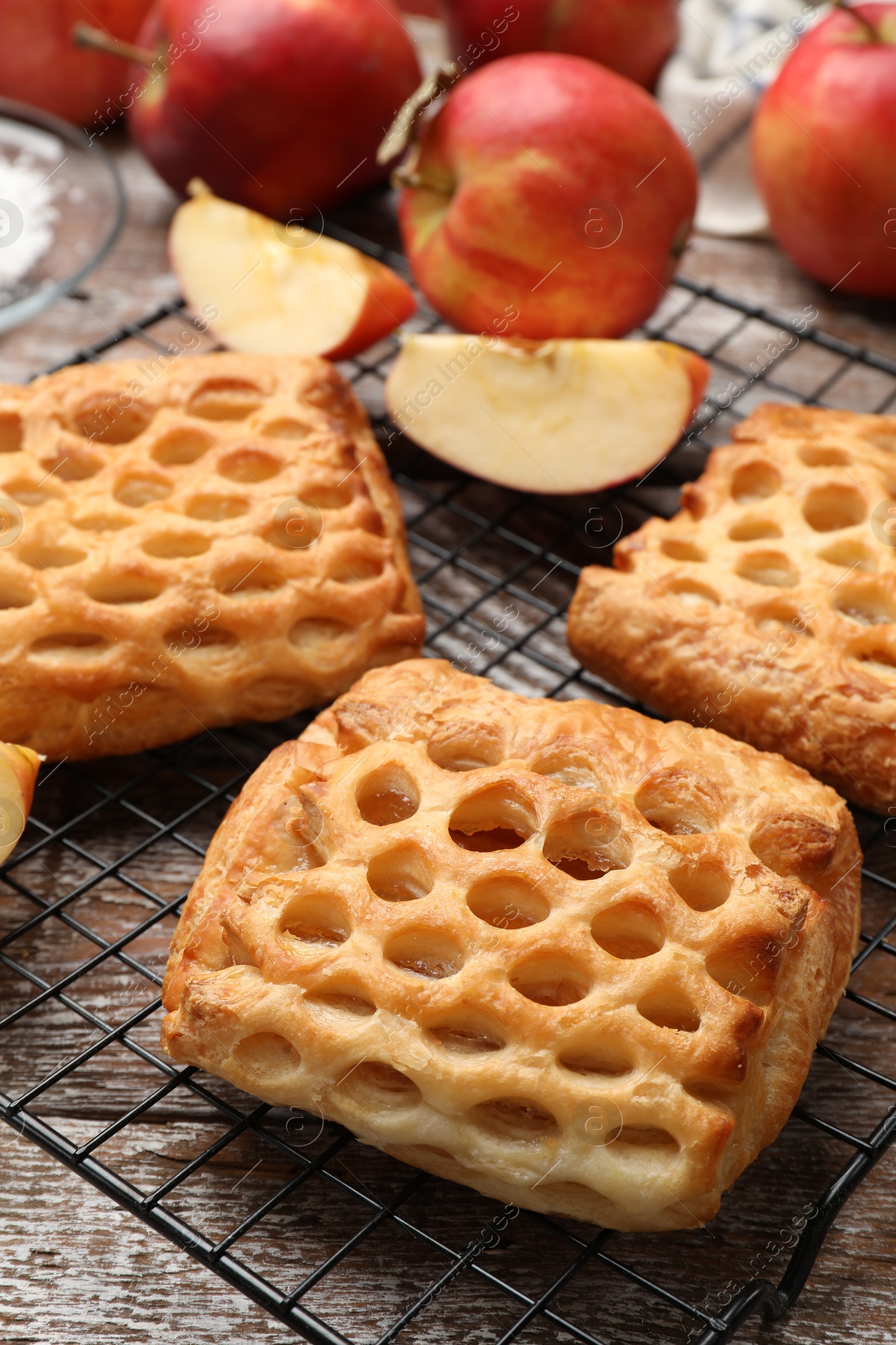 Photo of Delicious puff pastries with fruit filling and apples on wooden table, closeup