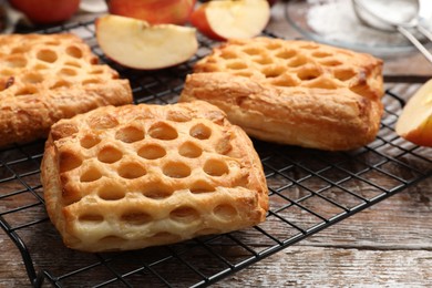 Photo of Delicious puff pastries with fruit filling and apples on wooden table, closeup