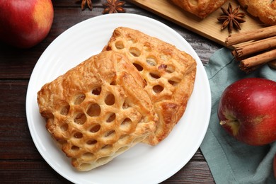 Delicious puff pastries, apples, cinnamon and anise stars on wooden table, top view