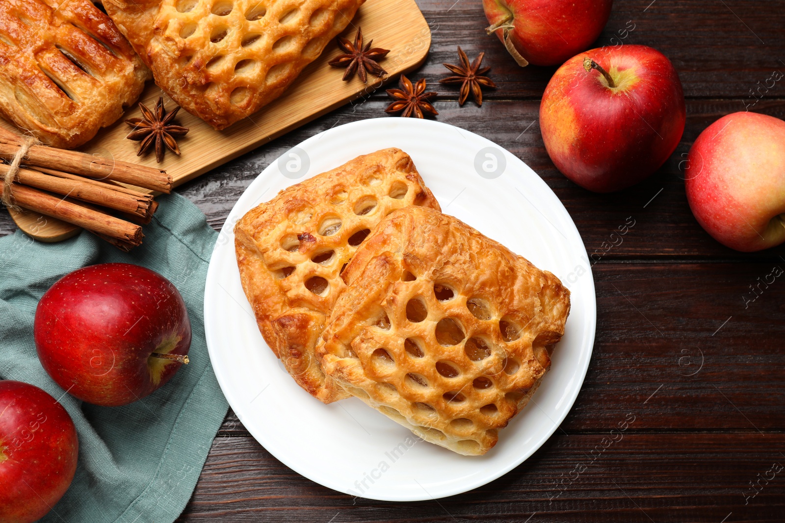 Photo of Delicious puff pastries, apples, cinnamon and anise stars on wooden table, top view