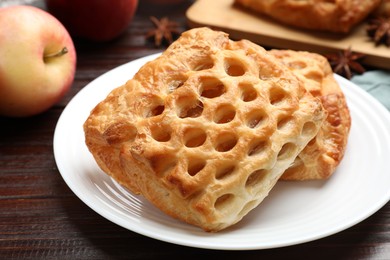 Delicious puff pastries with fruit filling on wooden table, closeup