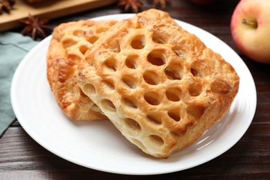 Delicious puff pastries with fruit filling on wooden table, closeup