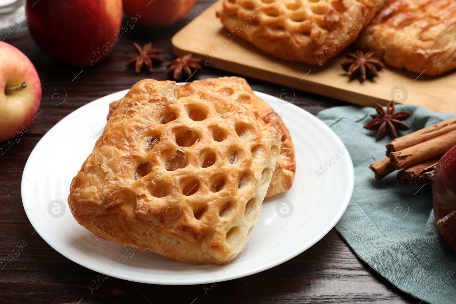 Photo of Delicious puff pastries, apples, cinnamon and anise stars on wooden table, closeup