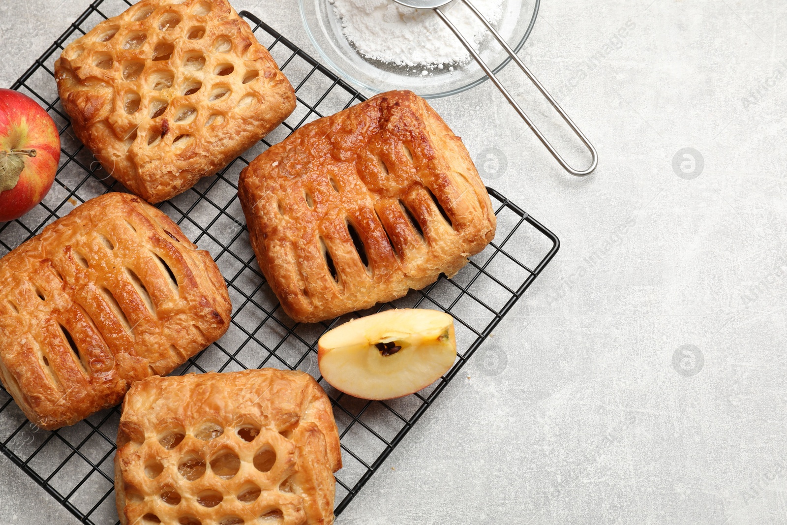 Photo of Delicious puff pastries with fruit filling and apples on grey table, top view. Space for text