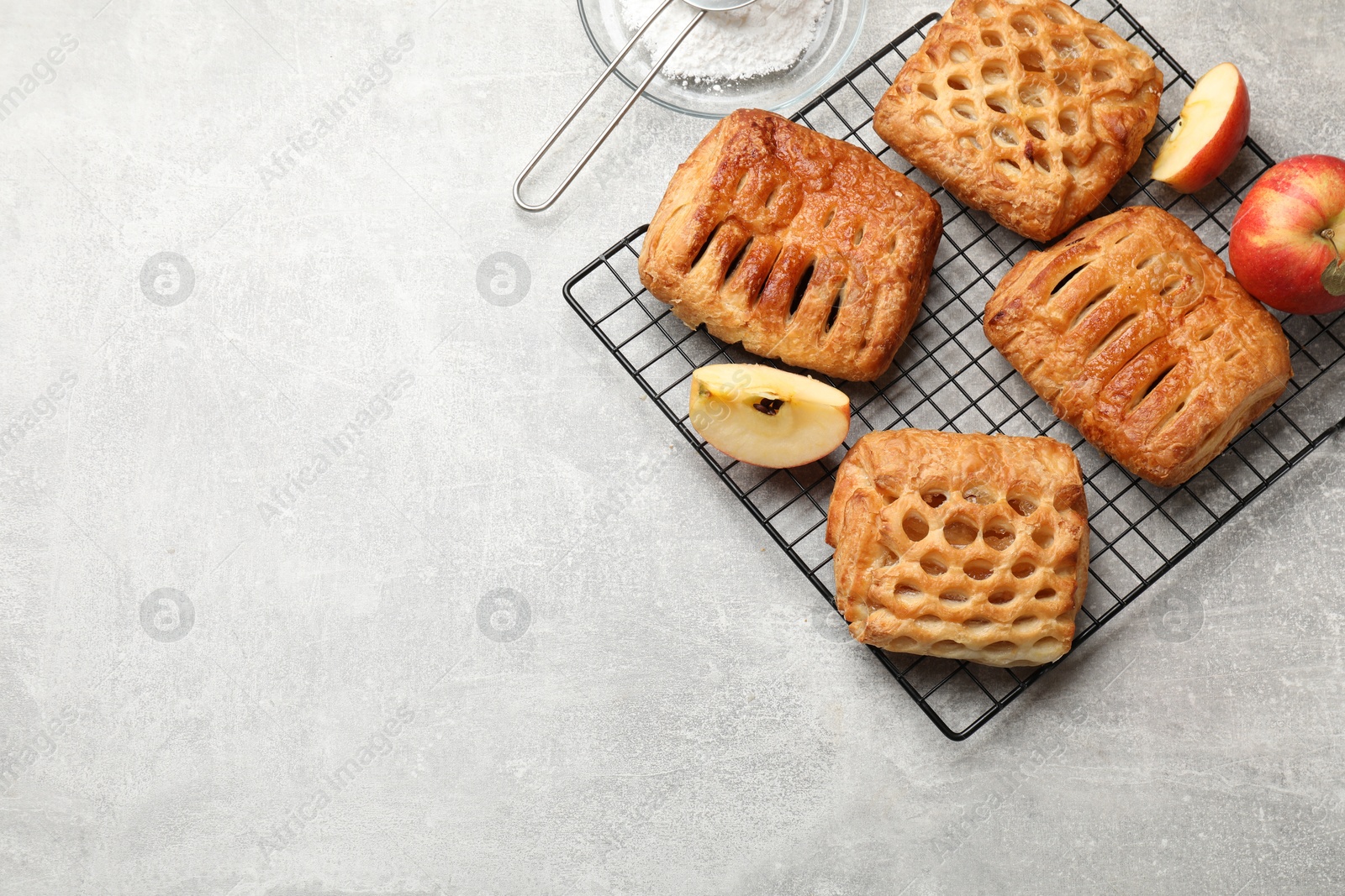 Photo of Delicious puff pastries with fruit filling and apples on grey table, top view. Space for text