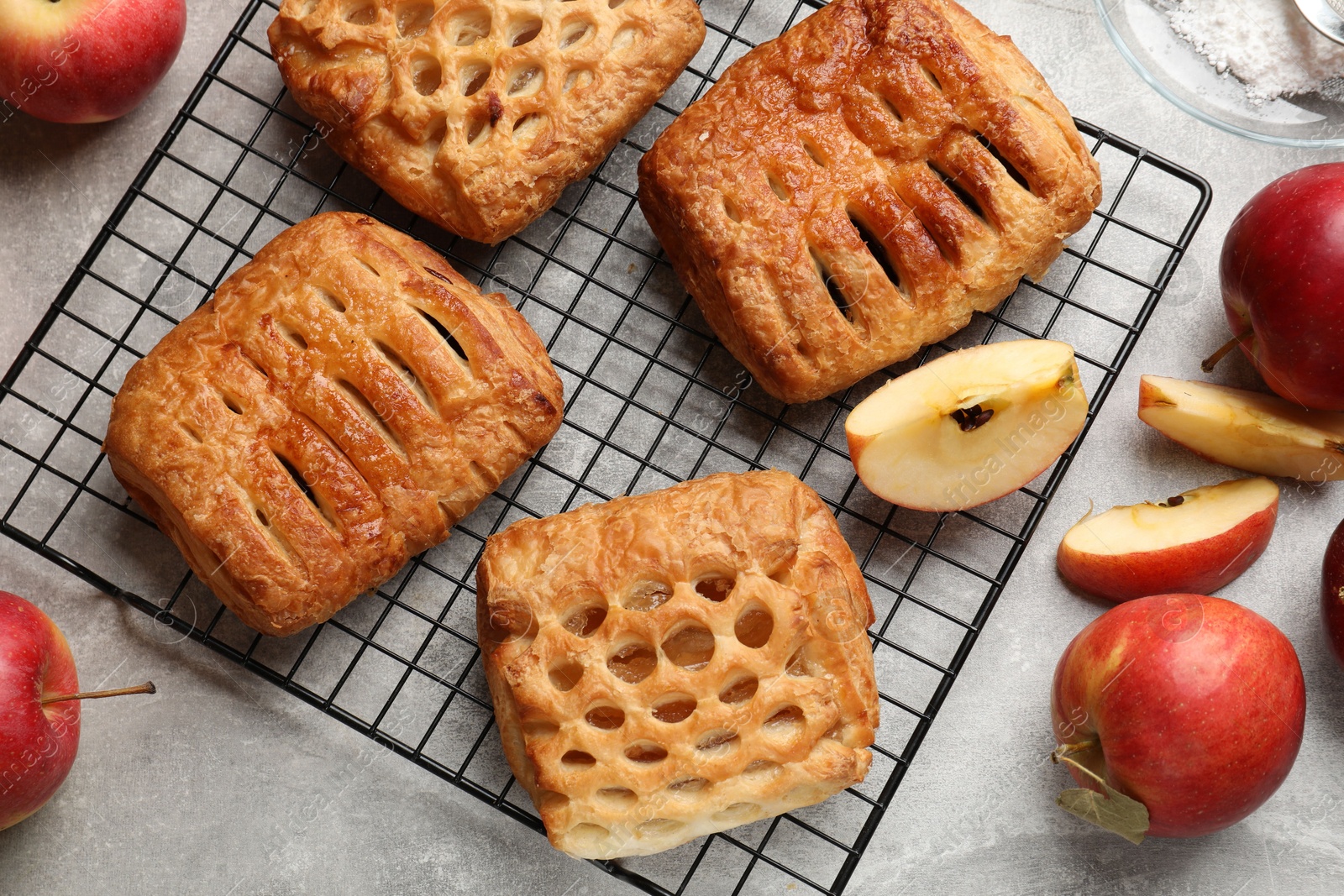 Photo of Delicious puff pastries with fruit filling and apples on grey table, top view