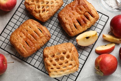 Photo of Delicious puff pastries with fruit filling and apples on grey table, top view