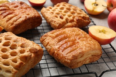 Delicious puff pastries with fruit filling and apples on grey table, closeup