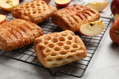 Photo of Delicious puff pastries with fruit filling and apples on grey table, closeup