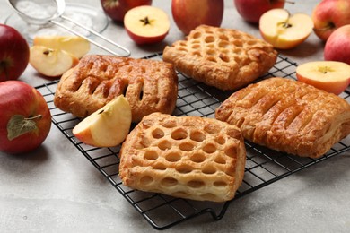 Photo of Delicious puff pastries with fruit filling and apples on grey table, closeup