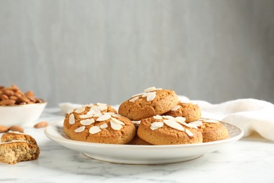 Photo of Tasty cookies with almond flakes on white marble table, closeup