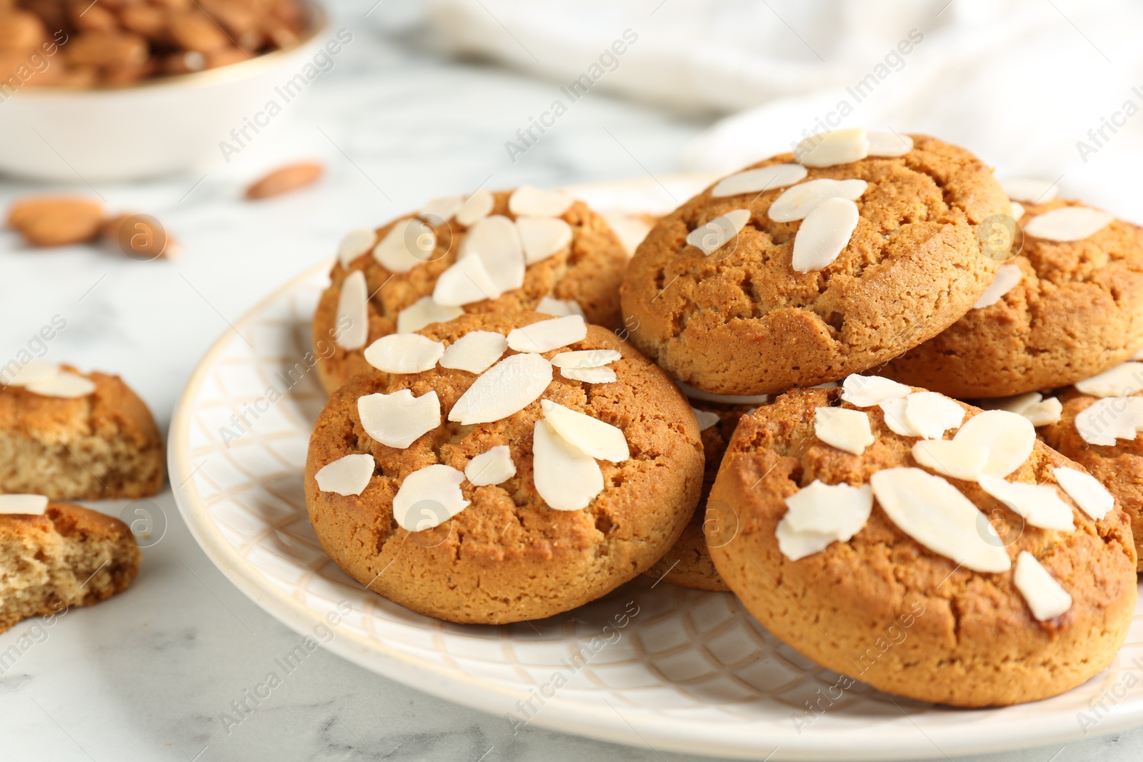 Photo of Tasty cookies with almond flakes on white marble table, closeup