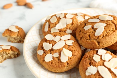 Photo of Tasty cookies with almond flakes on white marble table, closeup