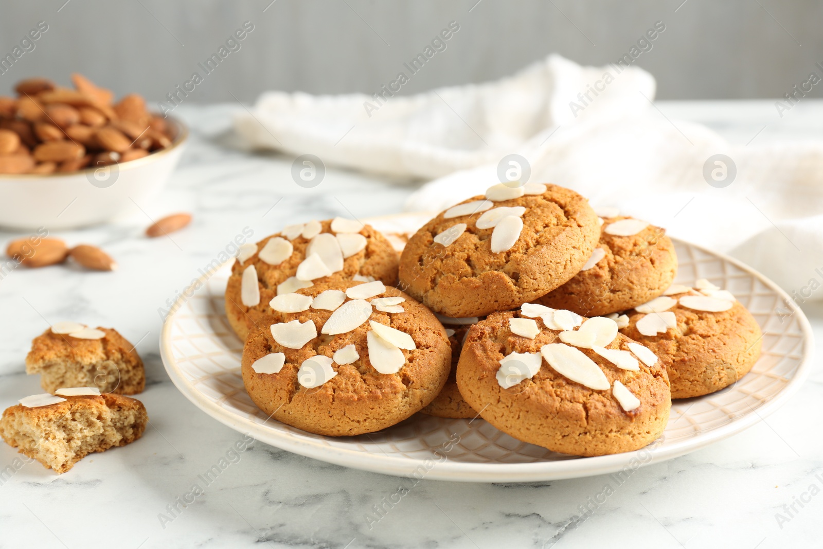 Photo of Tasty cookies with almond flakes and nuts on white marble table, closeup