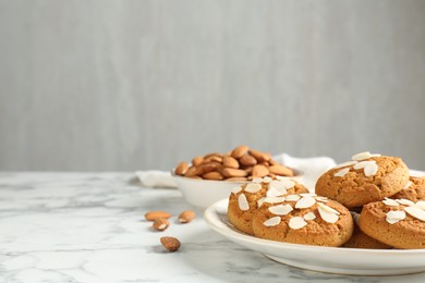 Photo of Tasty cookies with almond flakes and nuts on white marble table, closeup. Space for text