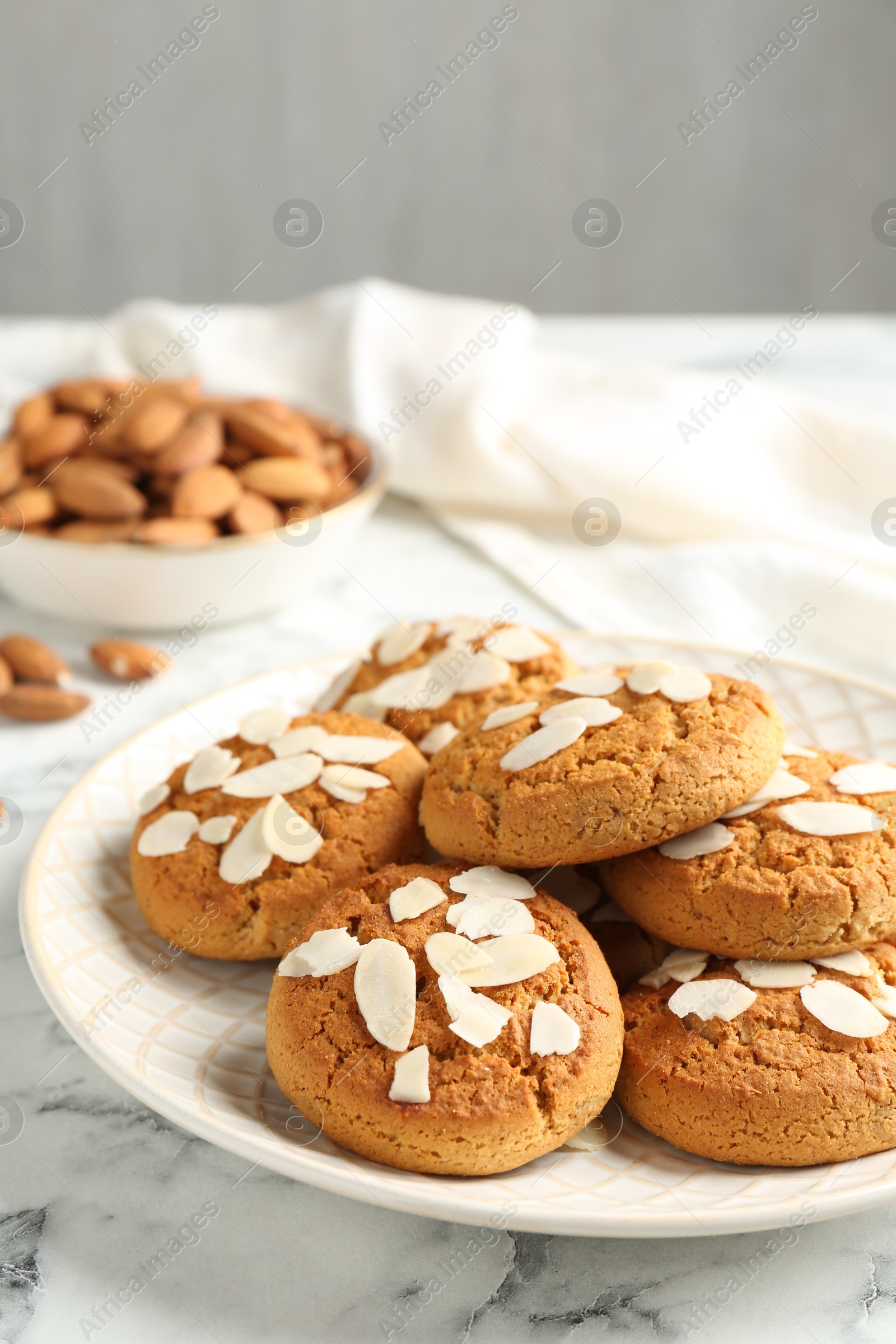 Photo of Tasty cookies with almond flakes and nuts on white marble table, closeup