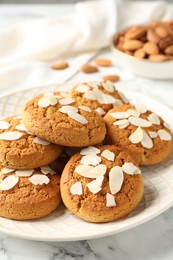 Photo of Tasty cookies with almond flakes and nuts on white marble table, closeup