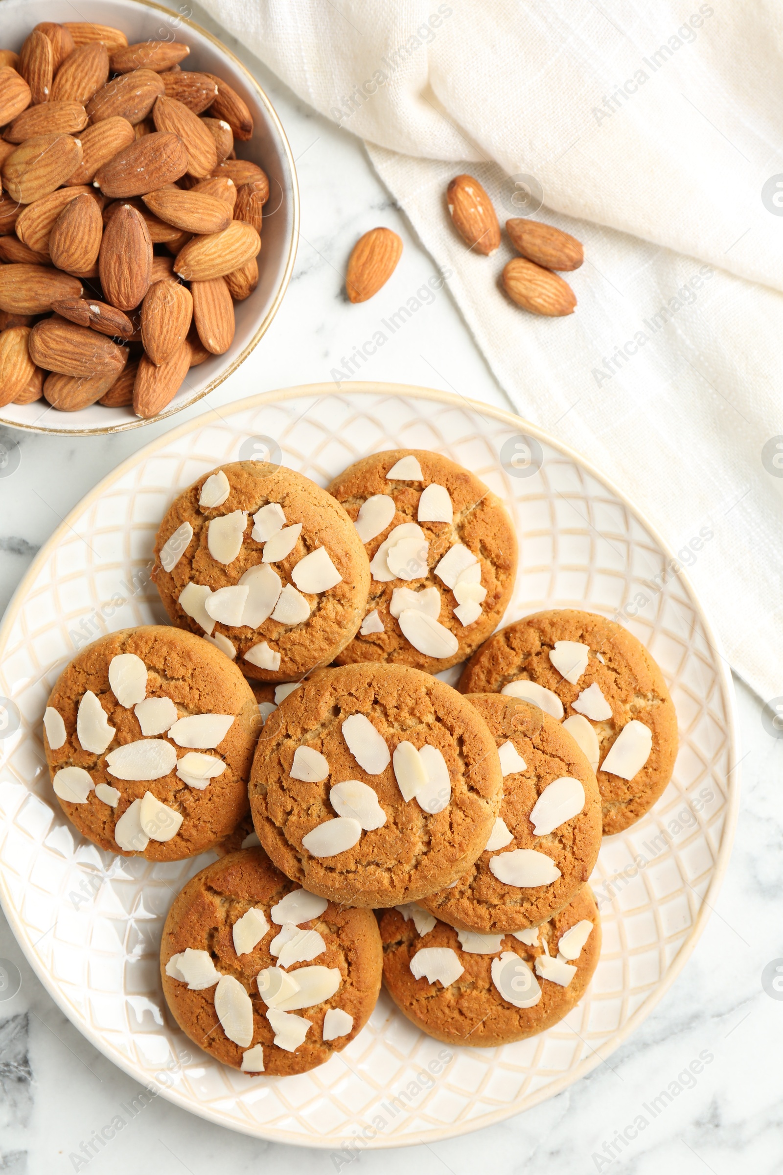 Photo of Tasty cookies with almond flakes and nuts on white marble table, top view