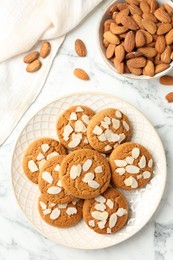 Photo of Tasty cookies with almond flakes and nuts on white marble table, top view