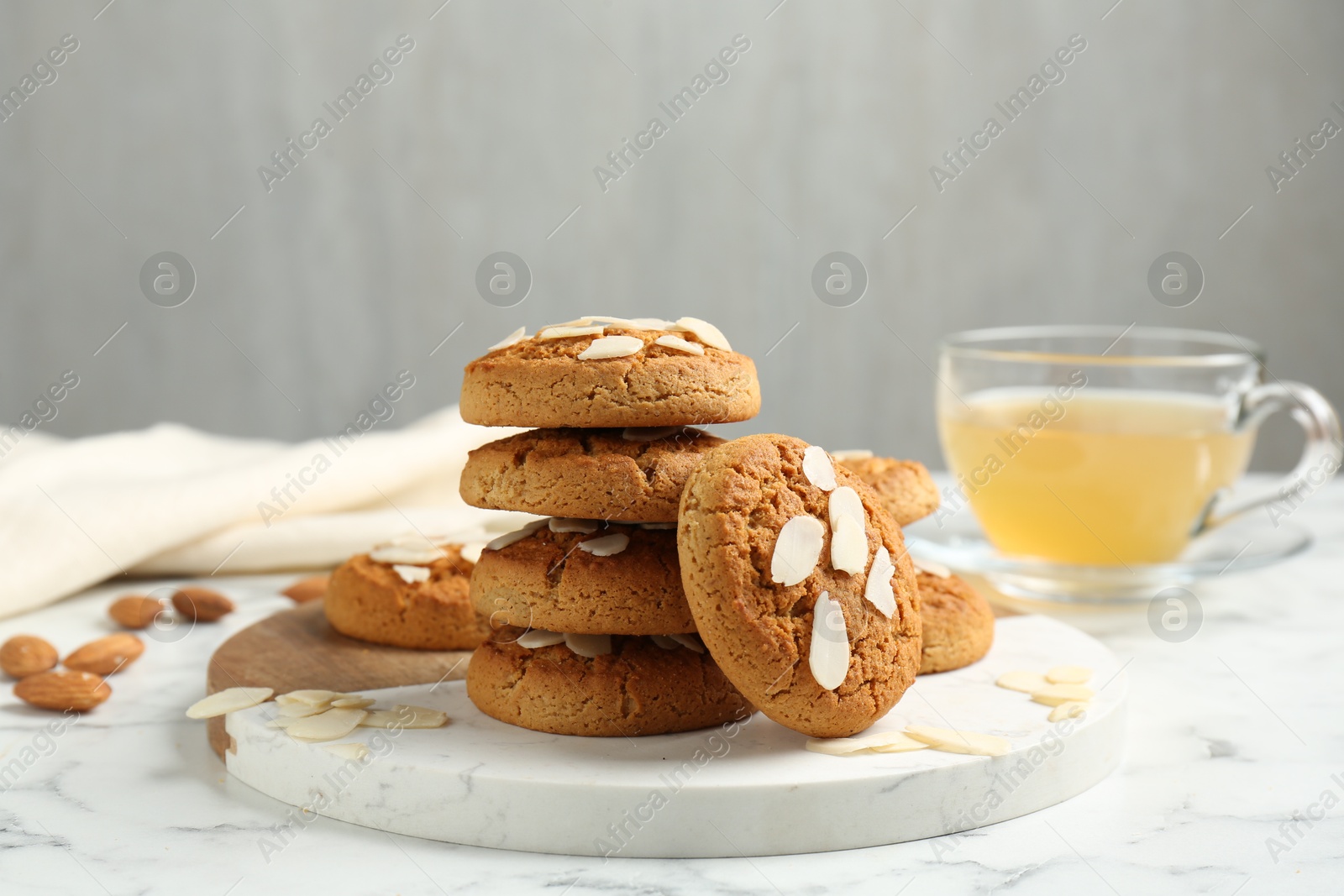 Photo of Tasty cookies with almond flakes and tea on white marble table