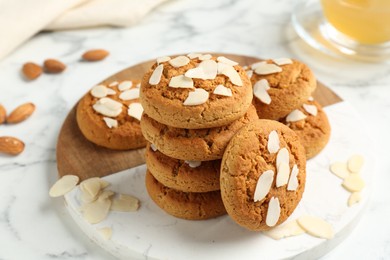 Photo of Tasty cookies with almond flakes on white marble table, closeup