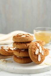 Photo of Tasty cookies with almond flakes and tea on table, closeup