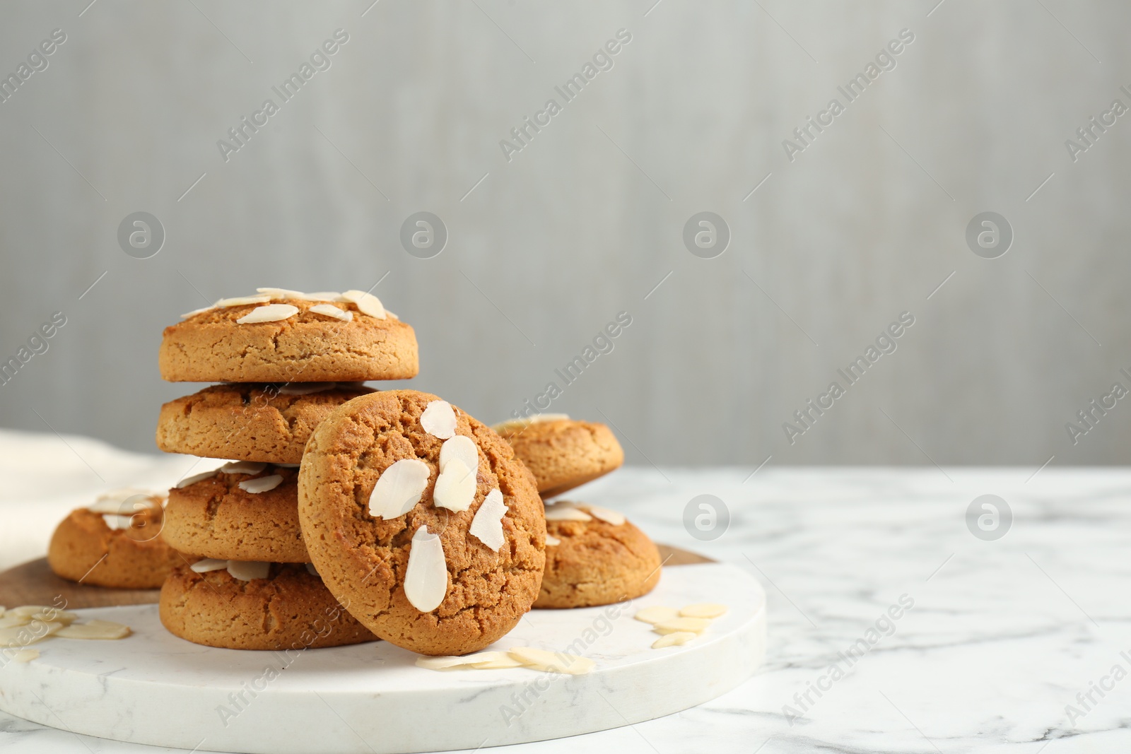 Photo of Tasty cookies with almond flakes on white marble table, space for text