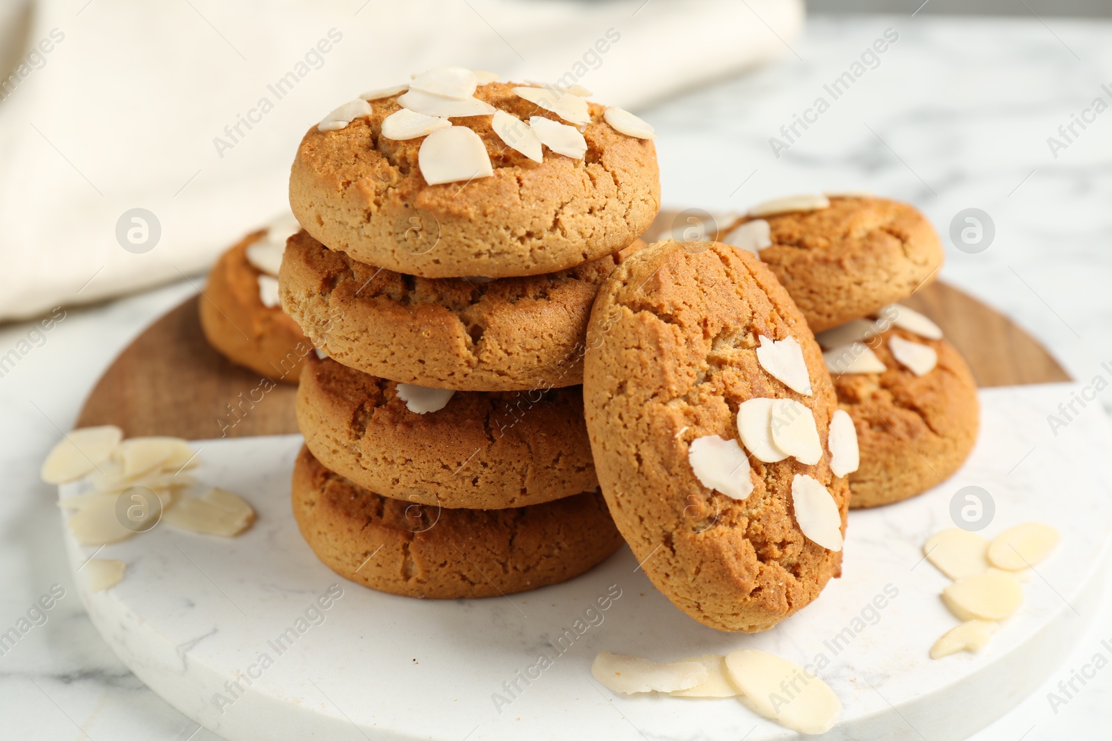 Photo of Tasty cookies with almond flakes on white marble table, closeup