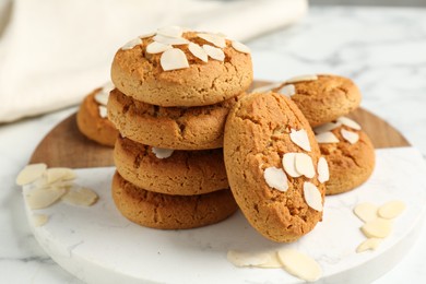 Photo of Tasty cookies with almond flakes on white marble table, closeup