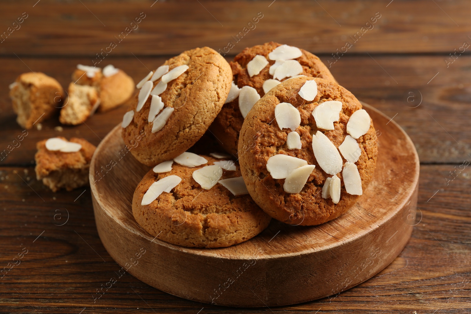 Photo of Tasty cookies with almond flakes on wooden table, closeup