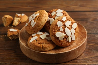 Photo of Tasty cookies with almond flakes on wooden table, closeup