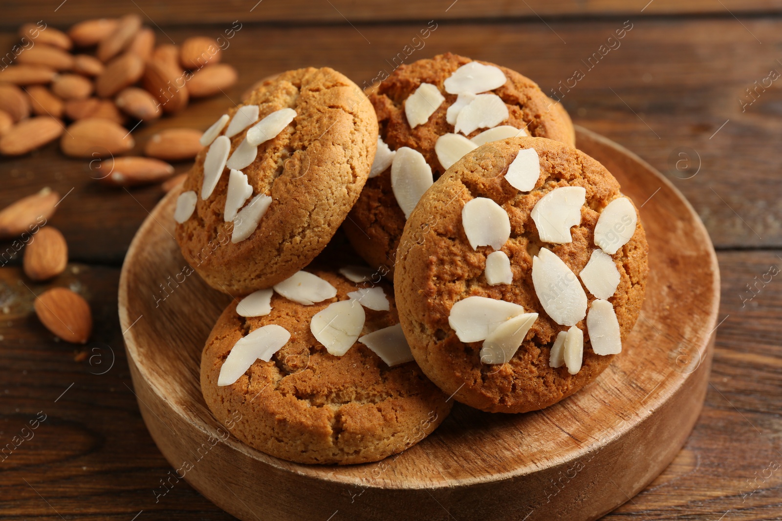 Photo of Tasty cookies with almond flakes and nuts on wooden table, closeup