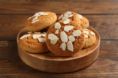 Photo of Tasty cookies with almond flakes on wooden table, closeup