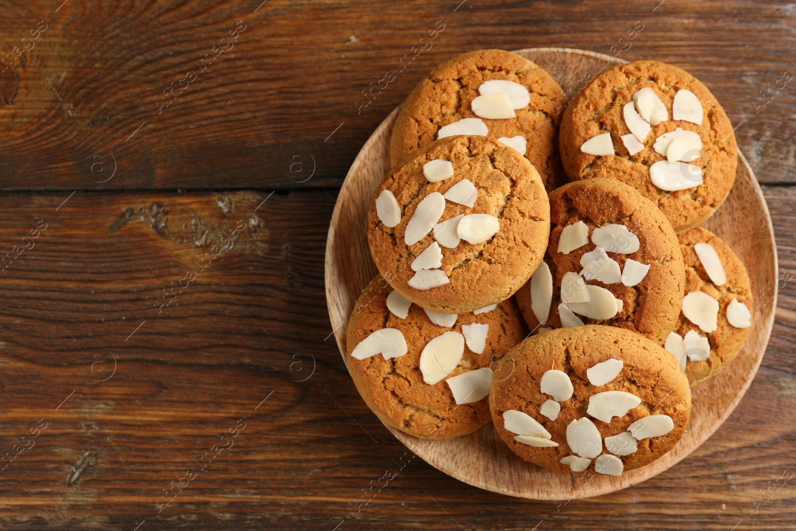 Photo of Tasty cookies with almond flakes on wooden table, top view. Space for text