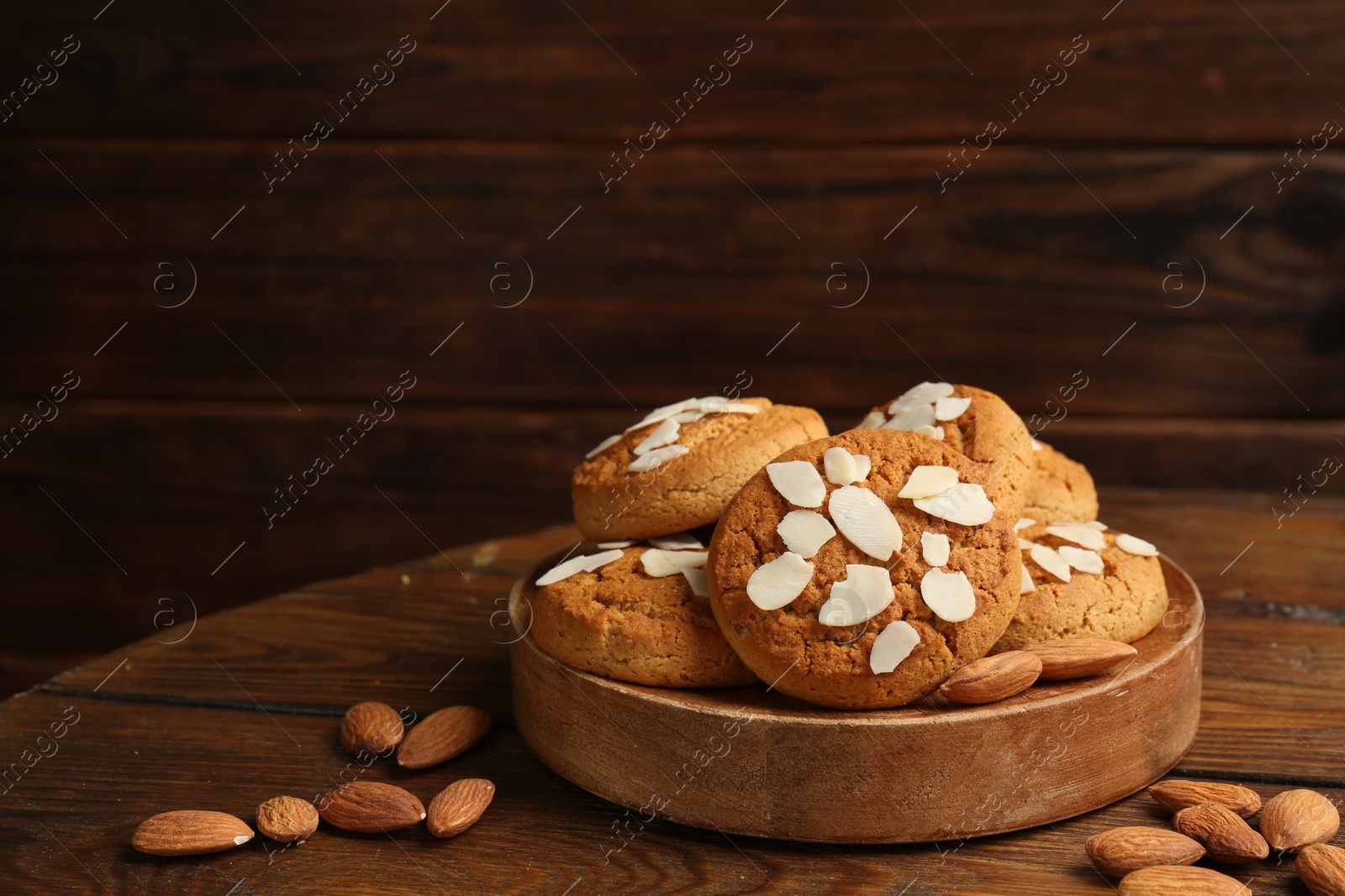 Photo of Tasty cookies with almond flakes and nuts on wooden table