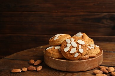 Photo of Tasty cookies with almond flakes and nuts on wooden table