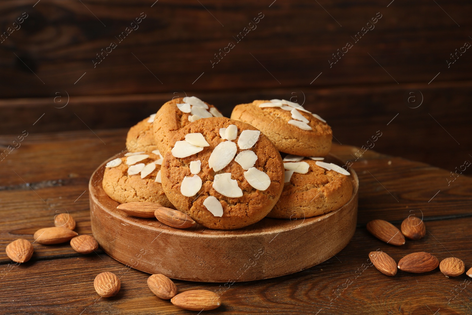 Photo of Tasty cookies with almond flakes and nuts on wooden table