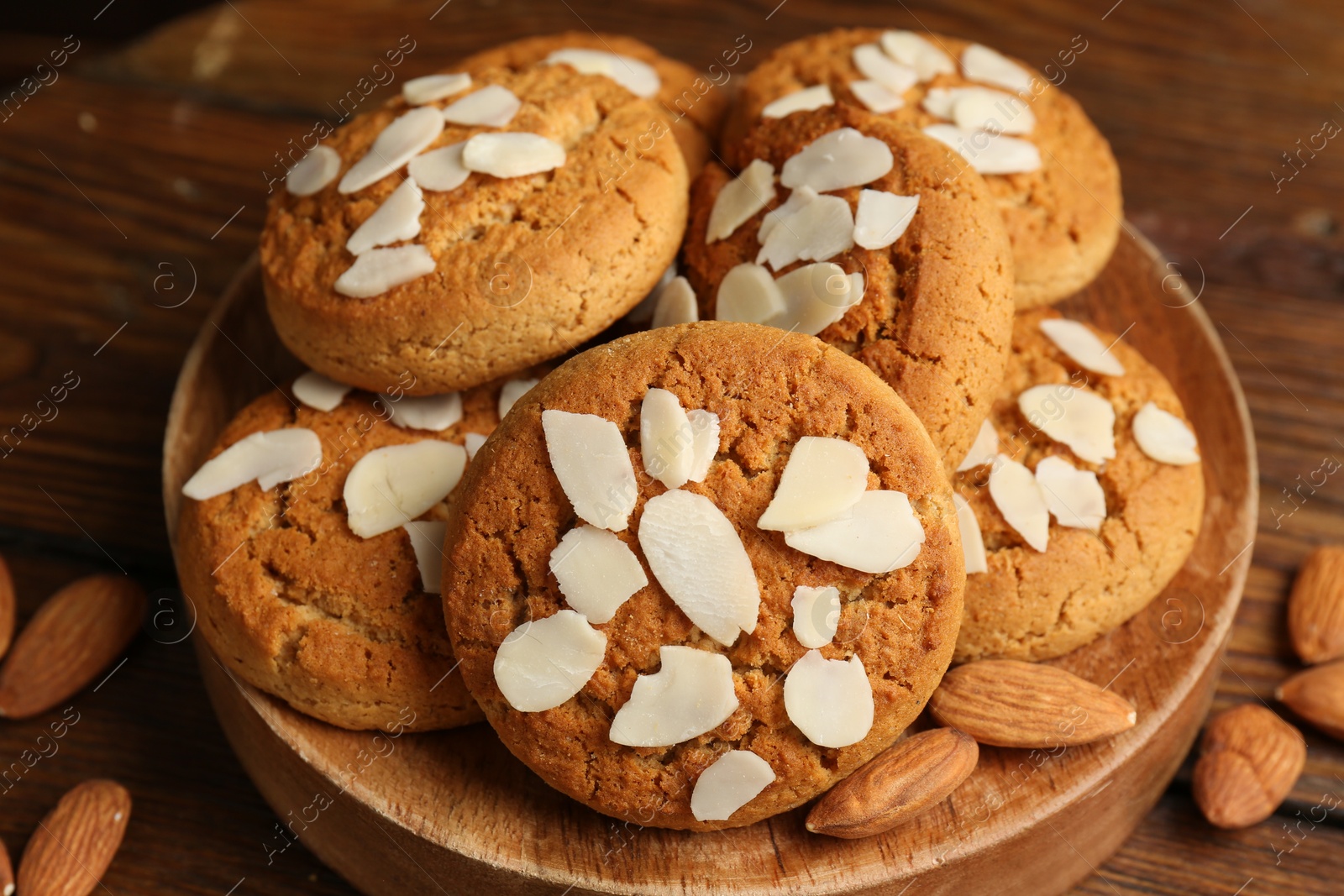 Photo of Tasty cookies with almond flakes and nuts on wooden table, closeup