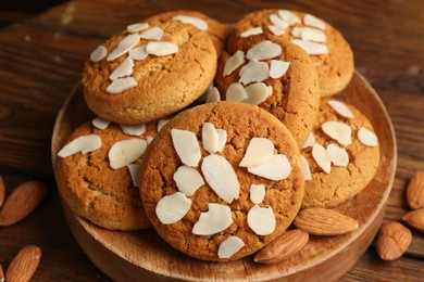 Tasty cookies with almond flakes and nuts on wooden table, closeup